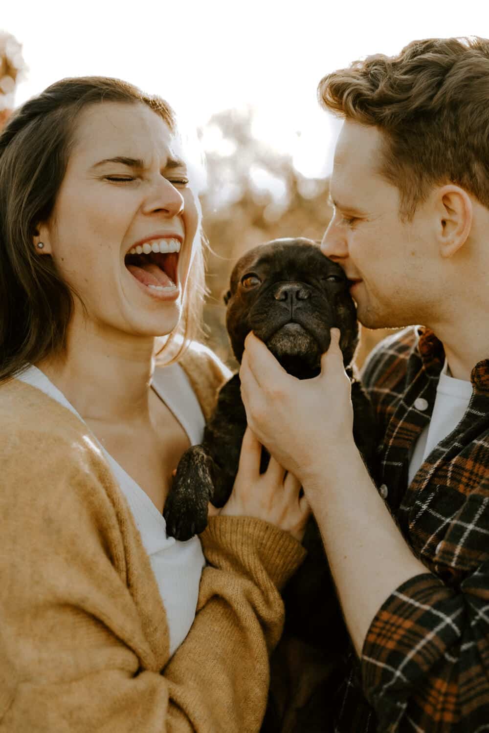 Ein Pärchen was mit ihrem Hund spielt und dabei lacht