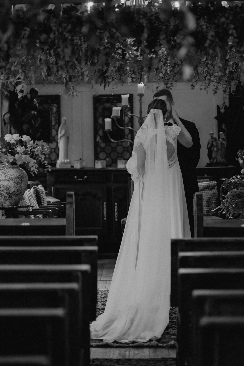 Kreative Hochzeitsbilder von Jessica & Lutz: Romantische Szene in der Kapelle des Ladüs, wo sie ihre Gelübde austauschen, umgeben von Familie und Freunden