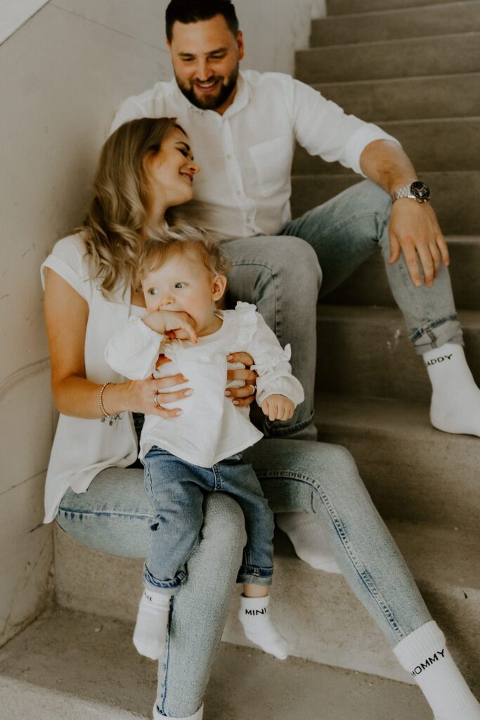 Familie mit Baby sitzt gemeinsam auf einer Treppe