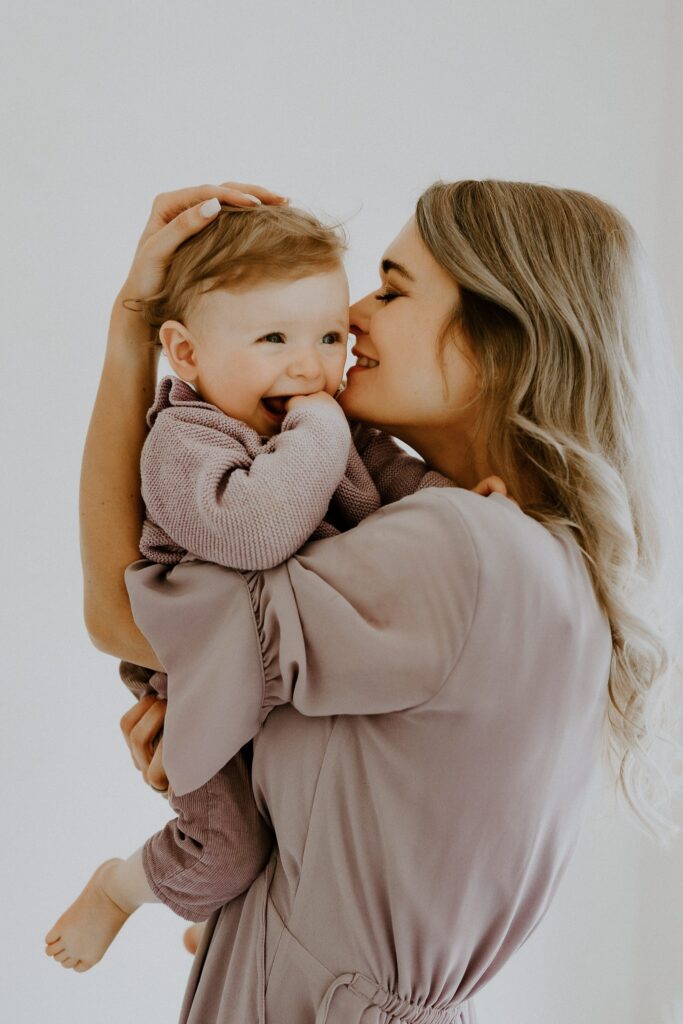 Mutter küsst ihr Baby auf den Kopf und trägt es auf dem Arm