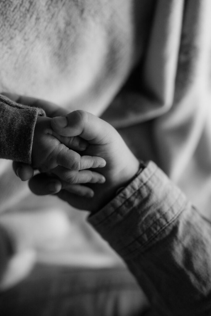 Schwarz-Weiß-Detail: Kinderhand in der Hand eines Erwachsenen