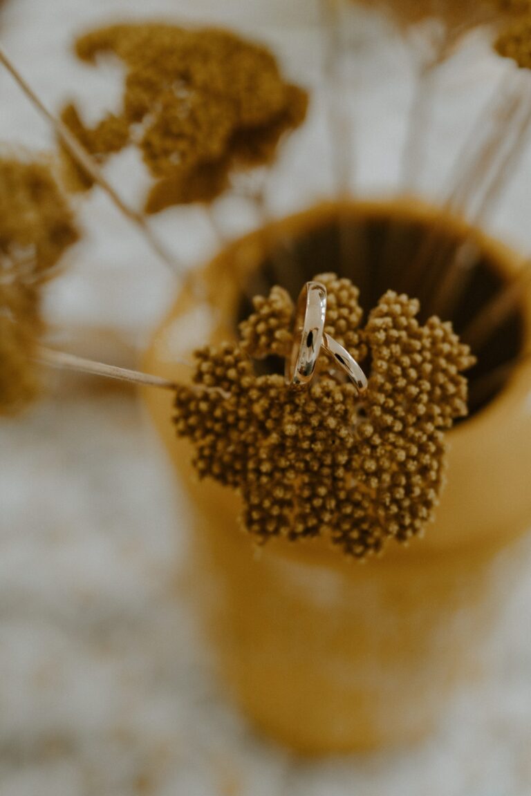 Detailaufnahme: Ring zwischen getrockneten Blüten in einer goldenen Schale