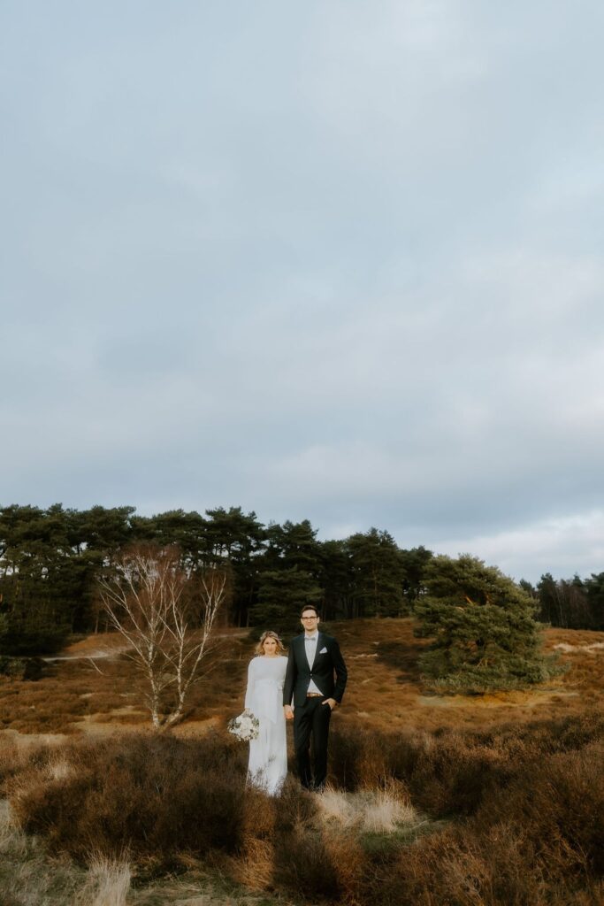 Brautpaar steht Hand in Hand in einer herbstlichen Heidelandschaft – Afterwedding Shooting NRW